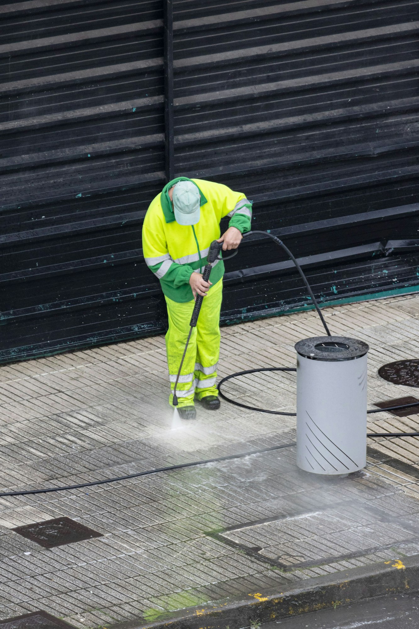 Worker cleaning a sidewalk with high pressure water jet machine